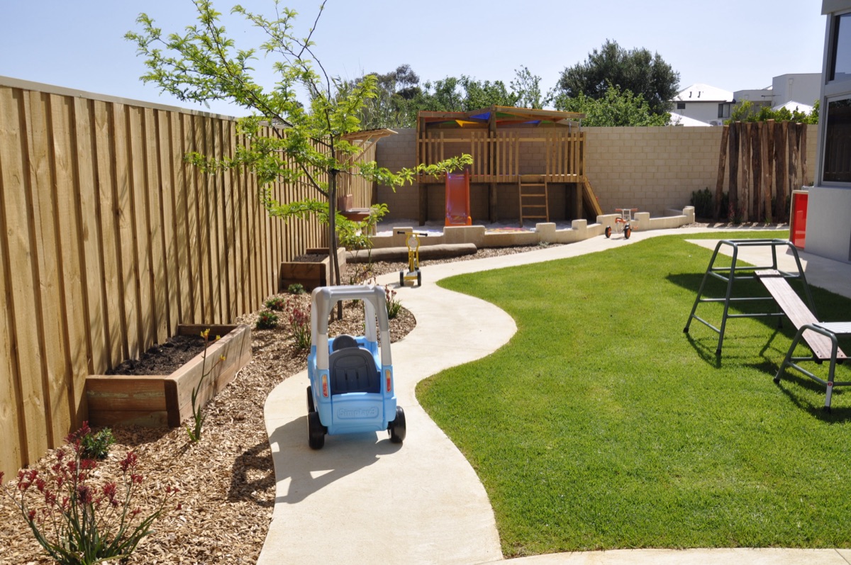 Sonas Woodbridge backyard playground — a fenced lawn with cubby house, sandpit, climbing frame and ride-on toys