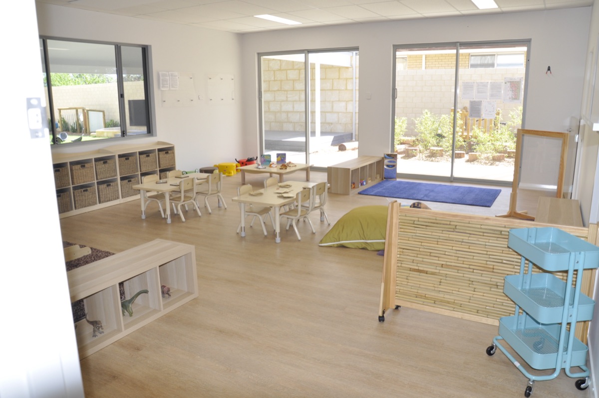An indoor studio at Sonas Woodbridge with kid-sized tables, woven storage and sliding doors opening to the garden