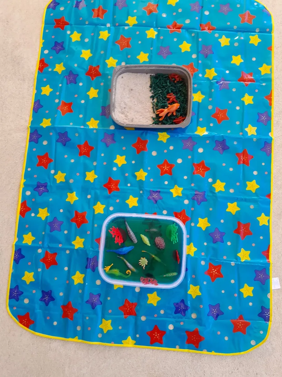 Toddler exploring Halloween-themed sensory bin with orange and black materials
