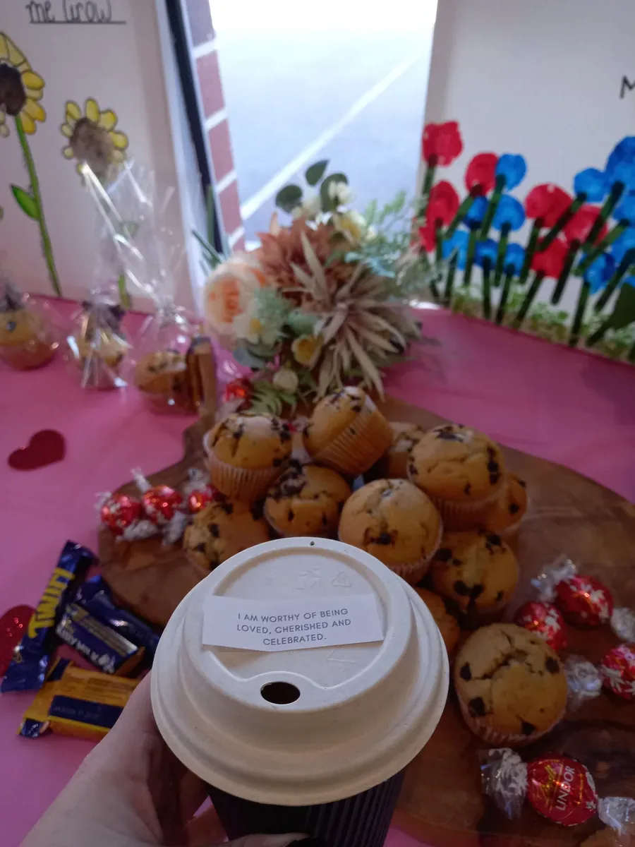 Toddler making a handprint Mother's Day card at daycare craft table